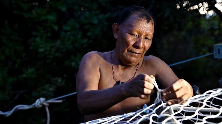 Indígena Waimiri-Atroari trançando ponte para travessia de animais arborícolas