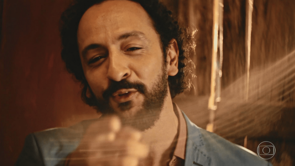 Bento (Irandhir Santos) entra no quarto, observa Santo (Domingos Montagner) deitado e ajeita a gravata do irmão, representado por uma câmera, em "Velho Chico" - Reprodução/TV Globo