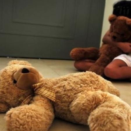 Foto ilustrativa sobre abuso infantil - criança abraça urso de pelúcia - Getty Images