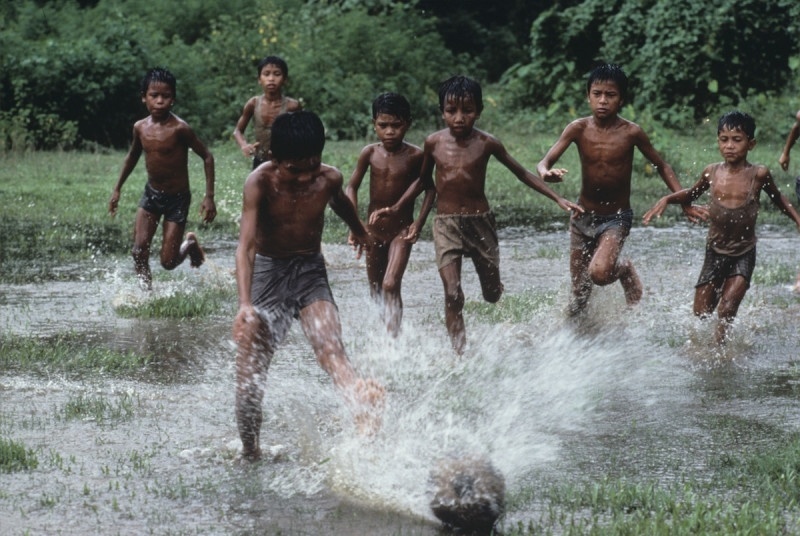Na versãoCrianças de Bangladesh jogam futebol em uma área alagada - Reprodução/Steve McCurry
