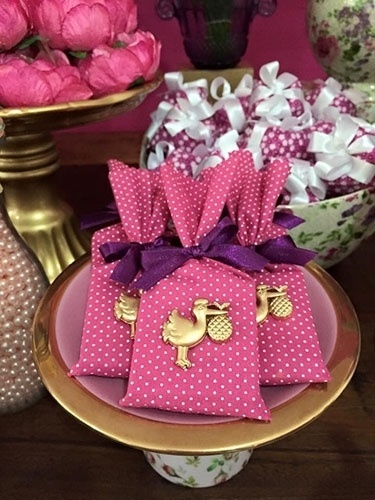 Sobre a mesa de bolo do chá de fraldas, barrinhas de chocolate, embaladas em tecido com estampa de poás, estavam em um porta-bolo. Atrás, alfajores de chocolate dispostos em cachepô de louça floral, ambos da Alugue para Festas - Divulgação