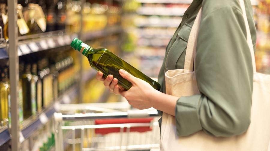 mulher no mercado segurando azeite - iStock