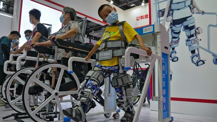 Menino usa exoesquetelo para pessoas com deficiência durante a última Conferência Mundial de Robótica, Pequim