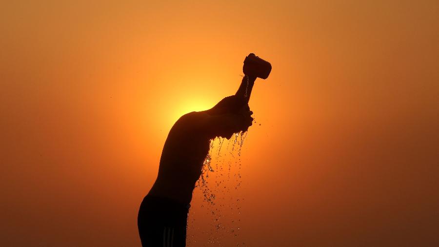 Homem se banha em um dia quente na Índia