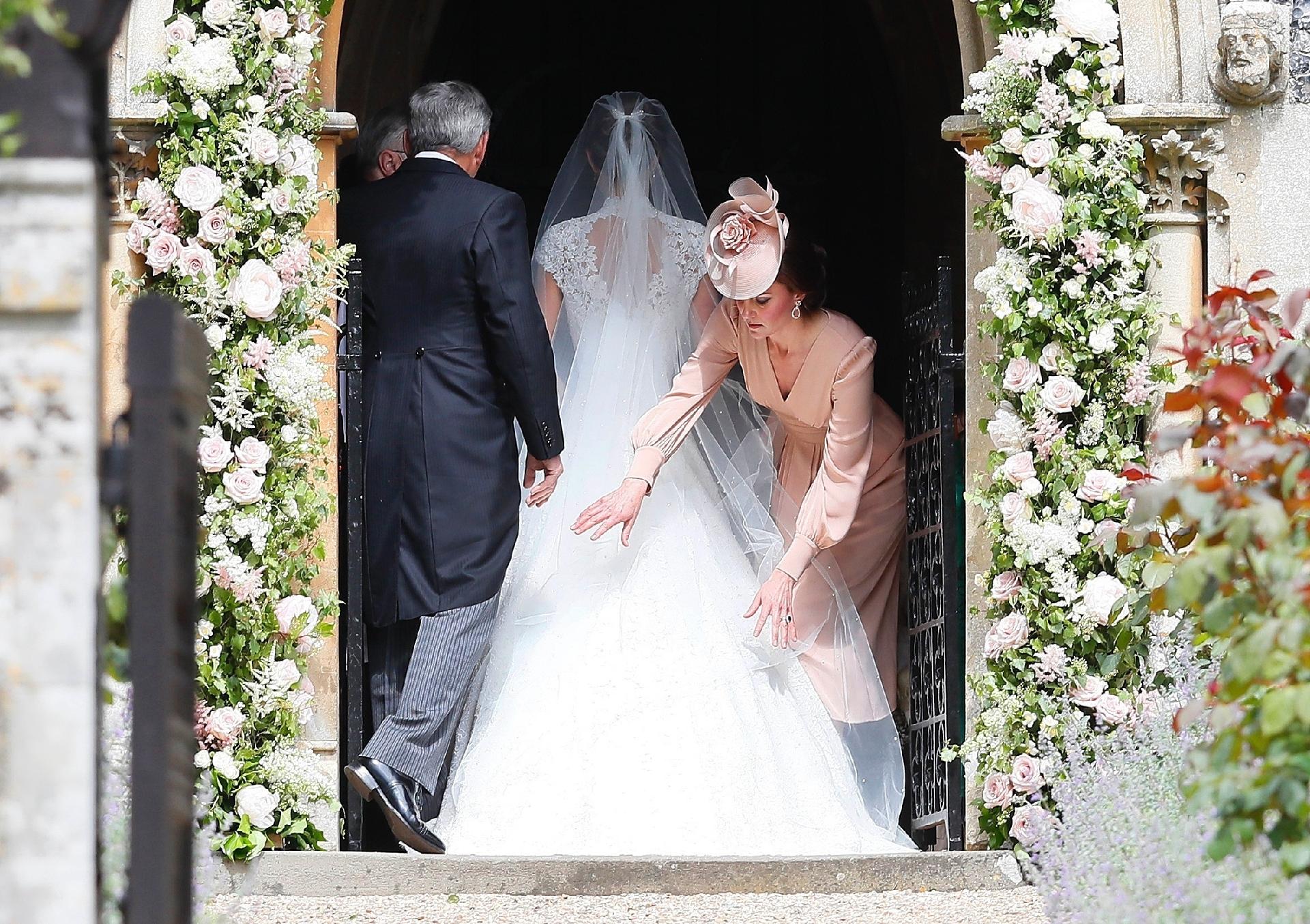 Gente como a gente! Kate Middleton arruma o vestido da irmã, Pippa, momentos antes de ela entrar na igreja  - Getty Images