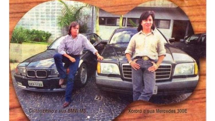 Em imagem dos anos 1990, Chitãozinho e Xororó posam com seus carrões