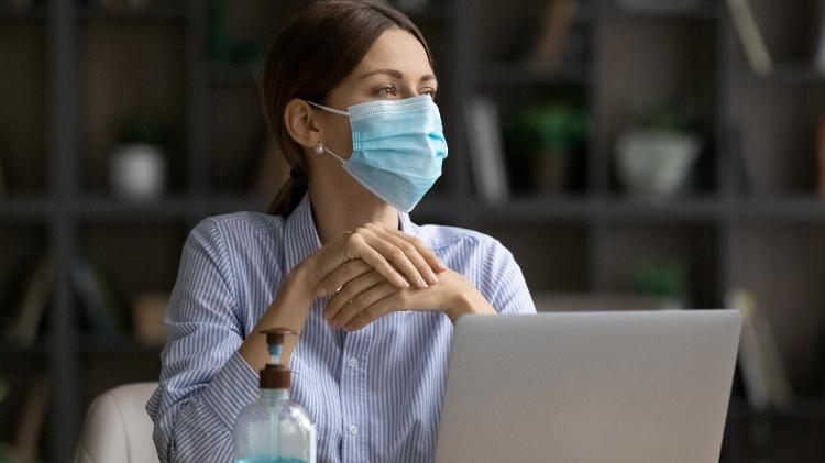 mulher no escritório usando máscara - iStock - iStock