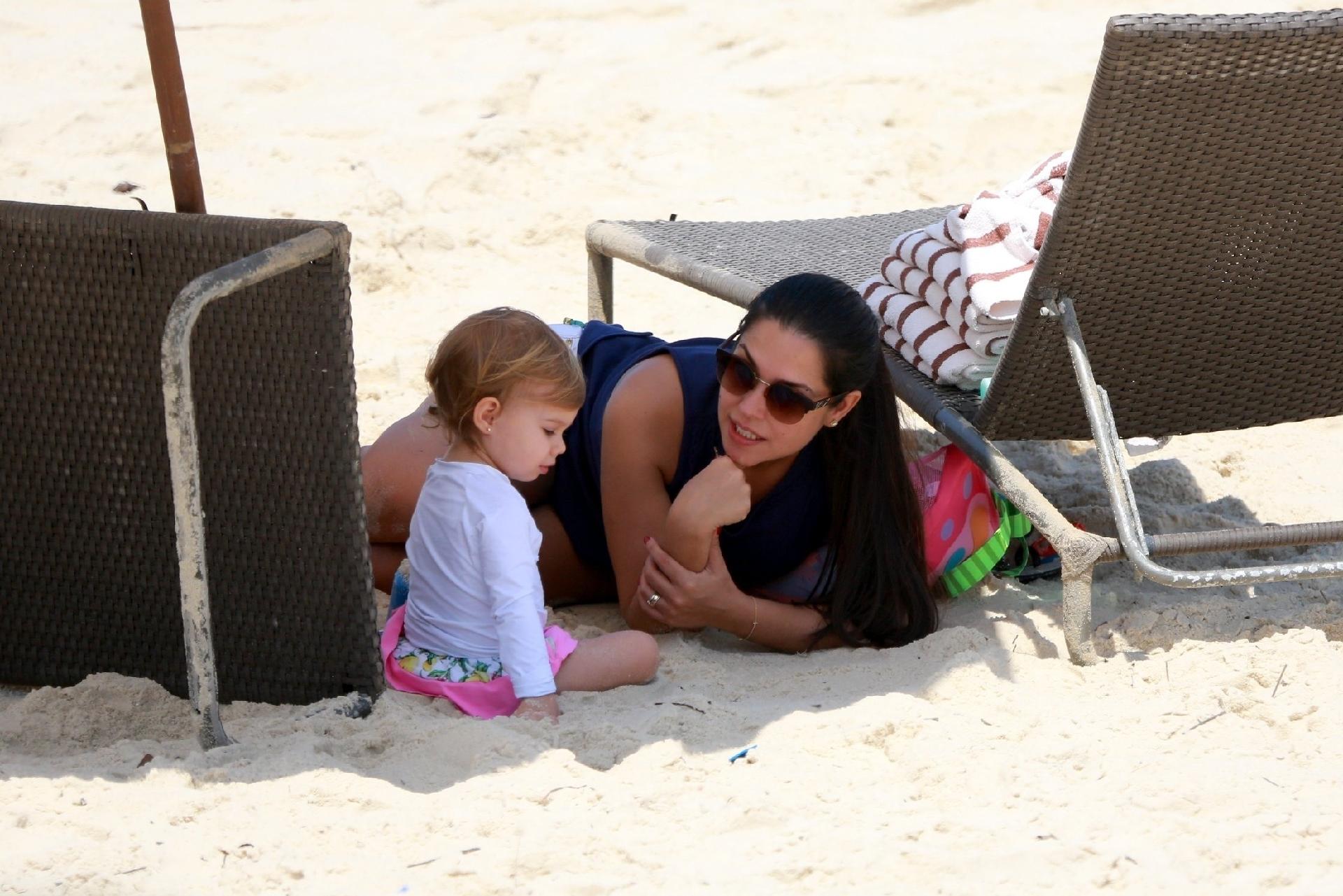 Thais presta atenção em Melinda, que conversa com a mãe enquanto brinca na areia - AgNews