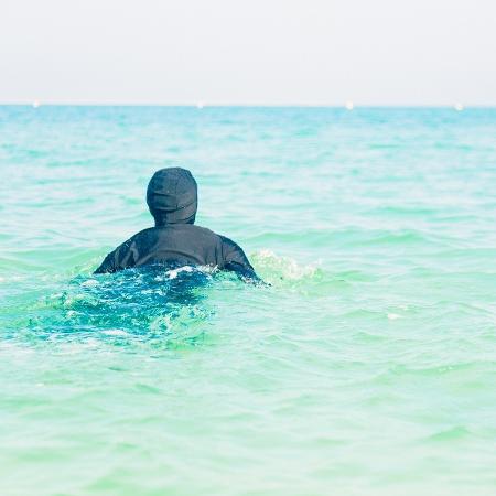 Mulher nada de burkini em praia de Dubai - iStock