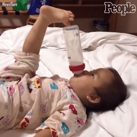Bebê apoia mamadeira no dedo do pé para tomar leite sem as mãos - Reprodução/People