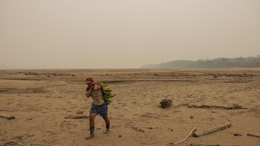 Agricultor caminha por faixa de areia que se formou no leito do rio Madeira em Rondônia