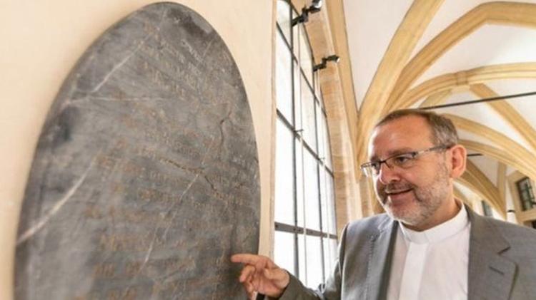 Oficial da igreja Norbert Jung com a lápide, que só ressurgiu recentemente - Dominik Schreiner via BBC - Dominik Schreiner via BBC