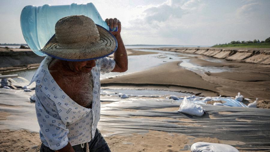 Homem carrega garrafão de água durante seca história no Amazonas em outubro de 2023 - Bruno Kelly/Reuters