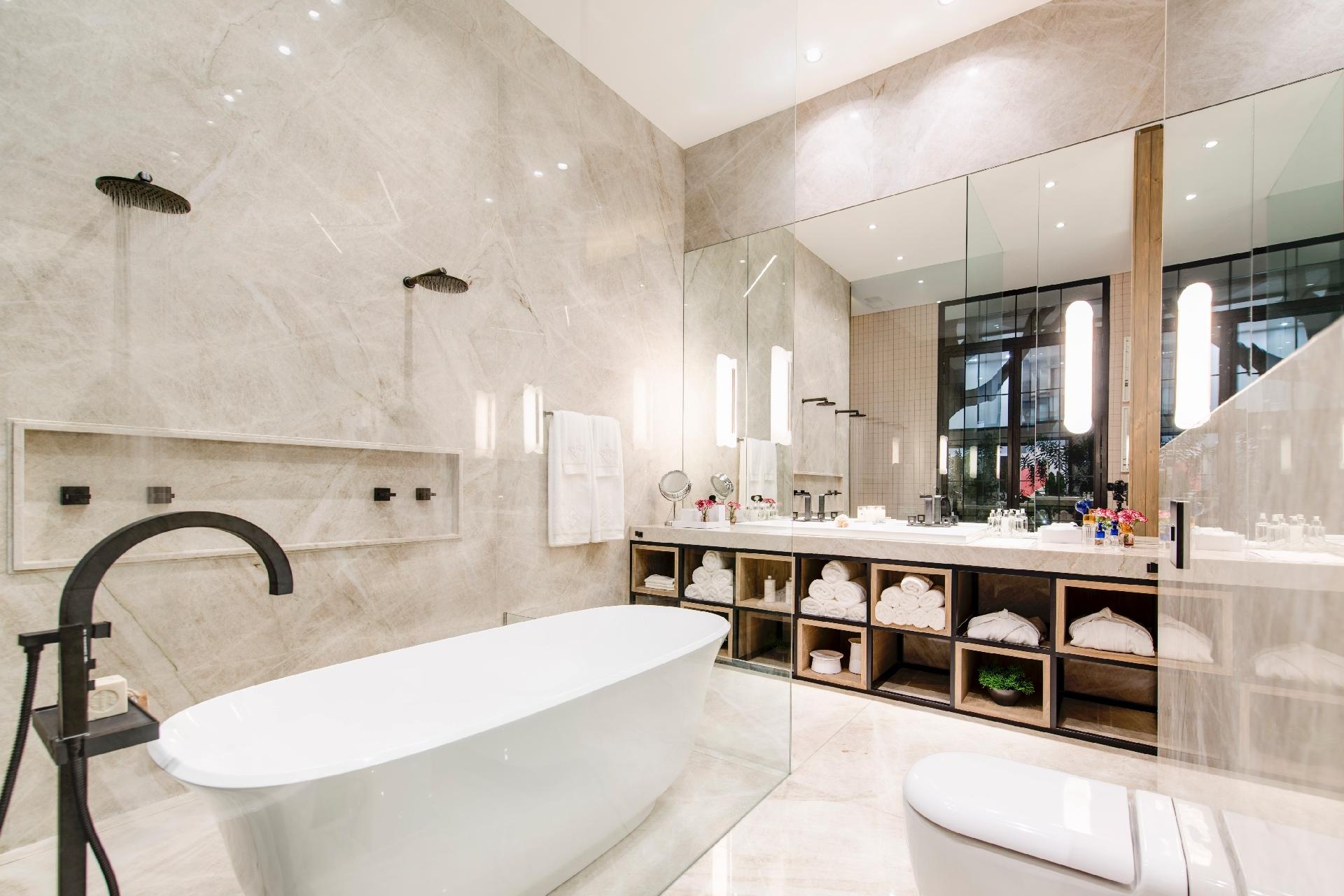 A imensa bancada do ambiente assinado por Marina Linhares, na Casa Cor SP, é de quartzito polido. As cubas são de encaixe e os metais prateados têm linhas retas. As roupas de banho, plantas e outros acessórios do ambiente ficam em caixas de madeira, que funcionam como nichos, logo abaixo do tampo de pedra - Katia Kuwabara/UOL