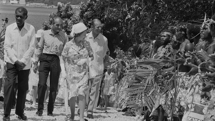 A rainha Elizabeth 2ª (à frente) e o príncipe Philip (ao fundo, à dir.) durante visita a Vanuatu em 1974 - McCabe/Getty Images - McCabe/Getty Images