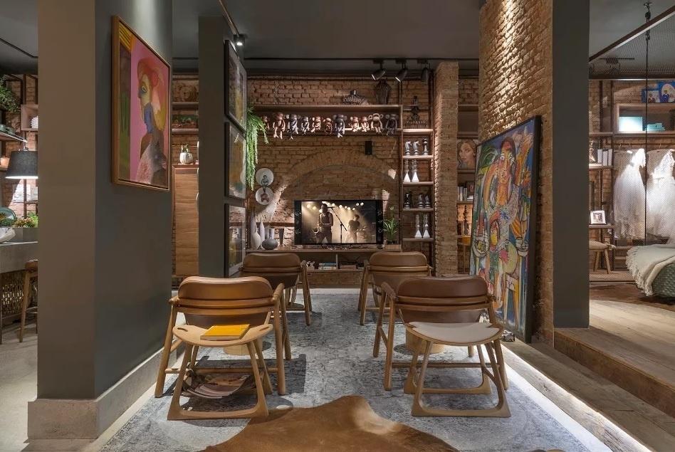 A estante com prateleiras feitas de aço corten transita de um cômodo a outro no loft Casa da Dinda, de Flávia Araújo, Juliana Resende e Ednara Borges. O espaço com 82 m², também conta com pé-direito alto e plantas na decoração. Na foto, o home theater é equipado com poltronas e bancos de madeira - Jomar Bragança/Divulgação