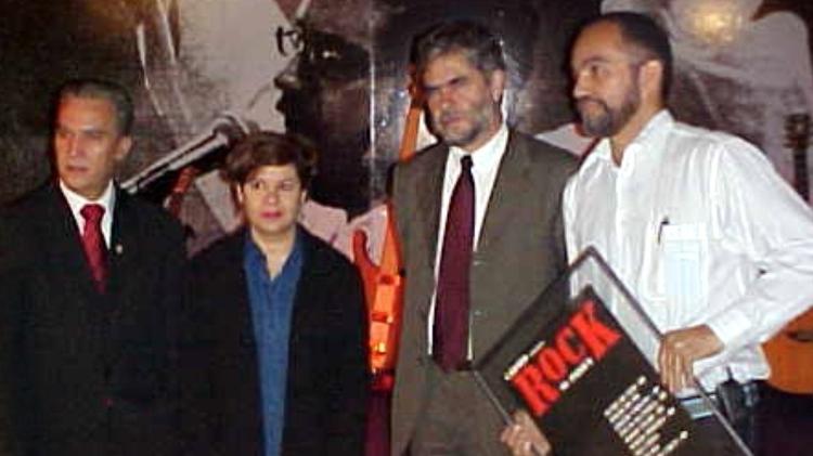 Carlos Alberto Xaulim (segurando o quadro) entrega para Carmem Manfredini, irmã de Renato Russo, uma cópia do cartaz do primeiro show do Legião Urbana - Divulgação - Divulgação