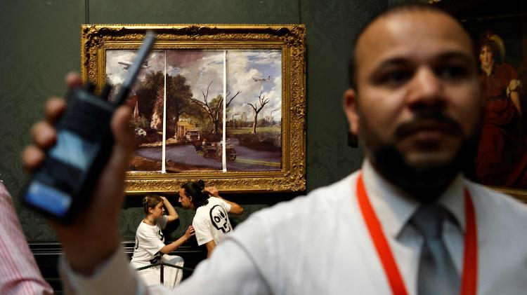 Casal se gruda em moldura do pintor inglês John Constable, em julho de 2022, em Londres - Carlos Jasso/AFP - Carlos Jasso/AFP