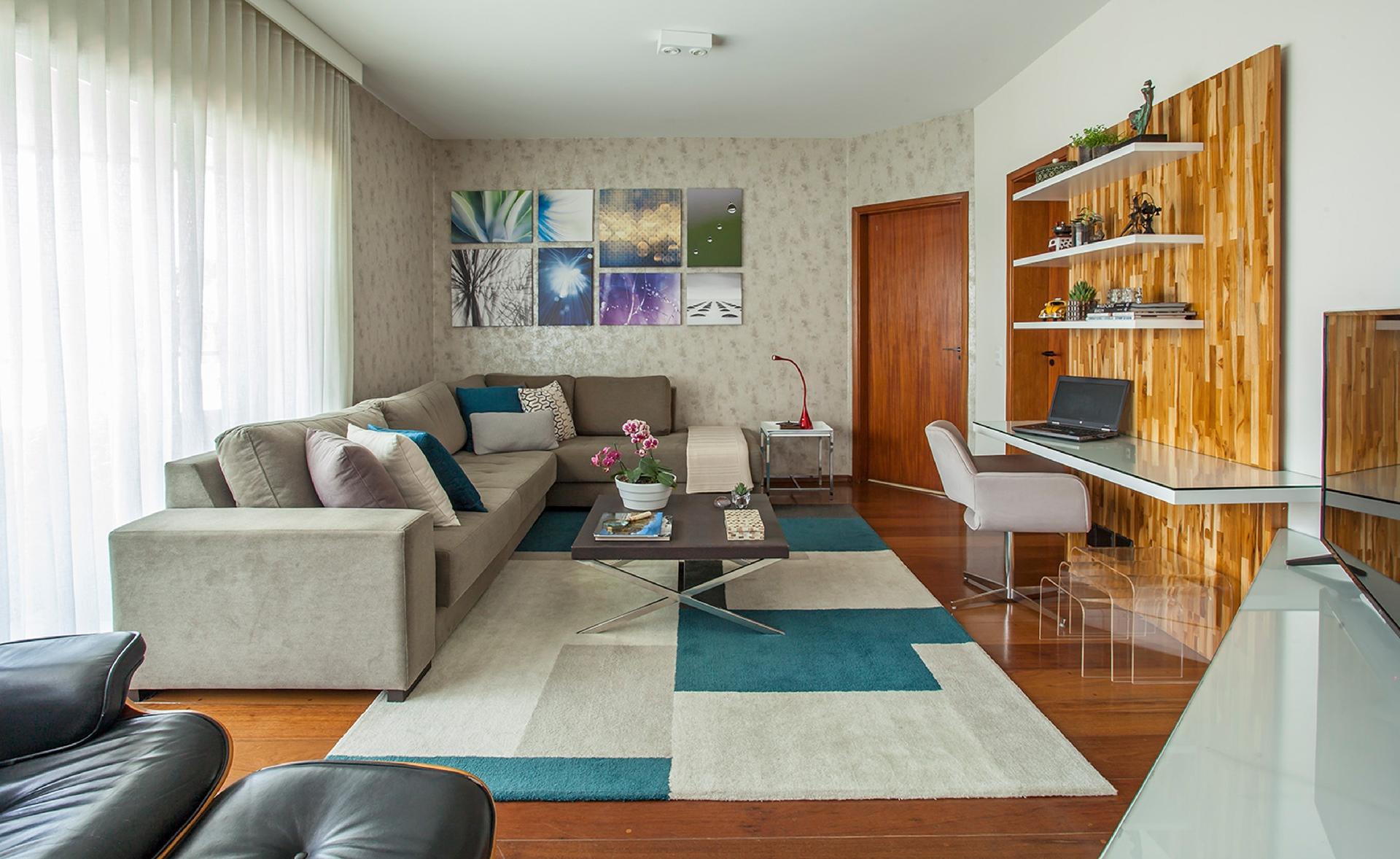 A sala é completa, pois funciona como estar, home theater e também escritório. Sem destoar do restante da decoração, o painel de madeira teca criado por Karina Korn concentra a mesa suspensa. Com braços e revestimento de tecido, a cadeira permite que os moradores passem horas na frente do computador. Banquinhos transparentes, de diversos tamanhos, servem de apoio para os pés ou ajudam no living - Eduardo Pozella | Divulgação