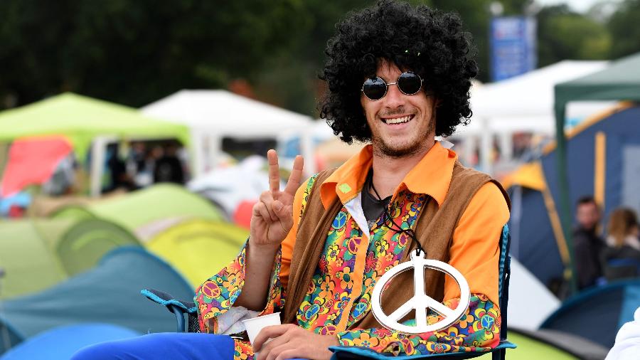 Homem vestido como se fosse um hippie faz gesto de "Paz e Amor" com os dedos - Fred Tanneau/AFP