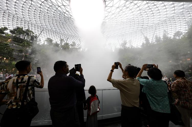 SINGAPORE - APRIL 11:  Visitors take photo of the Rain Vortex, a 40 metres high largest indoor waterfall in the world at the Jewel Changi Airport on April 11, 2023 in Singapore. Officially opening on April 17, Singapore's Changi Airport Jewel includes a 40-meter indoor waterfall contained under a steel-and-glass dome reportedly built for SGD 1.7 billion. (Photo by Suhaimi Abdullah/Getty Images) - Suhaimi Abdullah/Getty Images - Suhaimi Abdullah/Getty Images