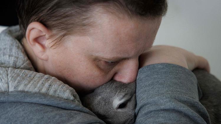 Lydie Imhoff sentada em sua cadeira de rodas abraçando seu coelho "Lucky" enquanto passava seu último dia em sua casa vazia em Besançon, França, em 30 de janeiro de 2024