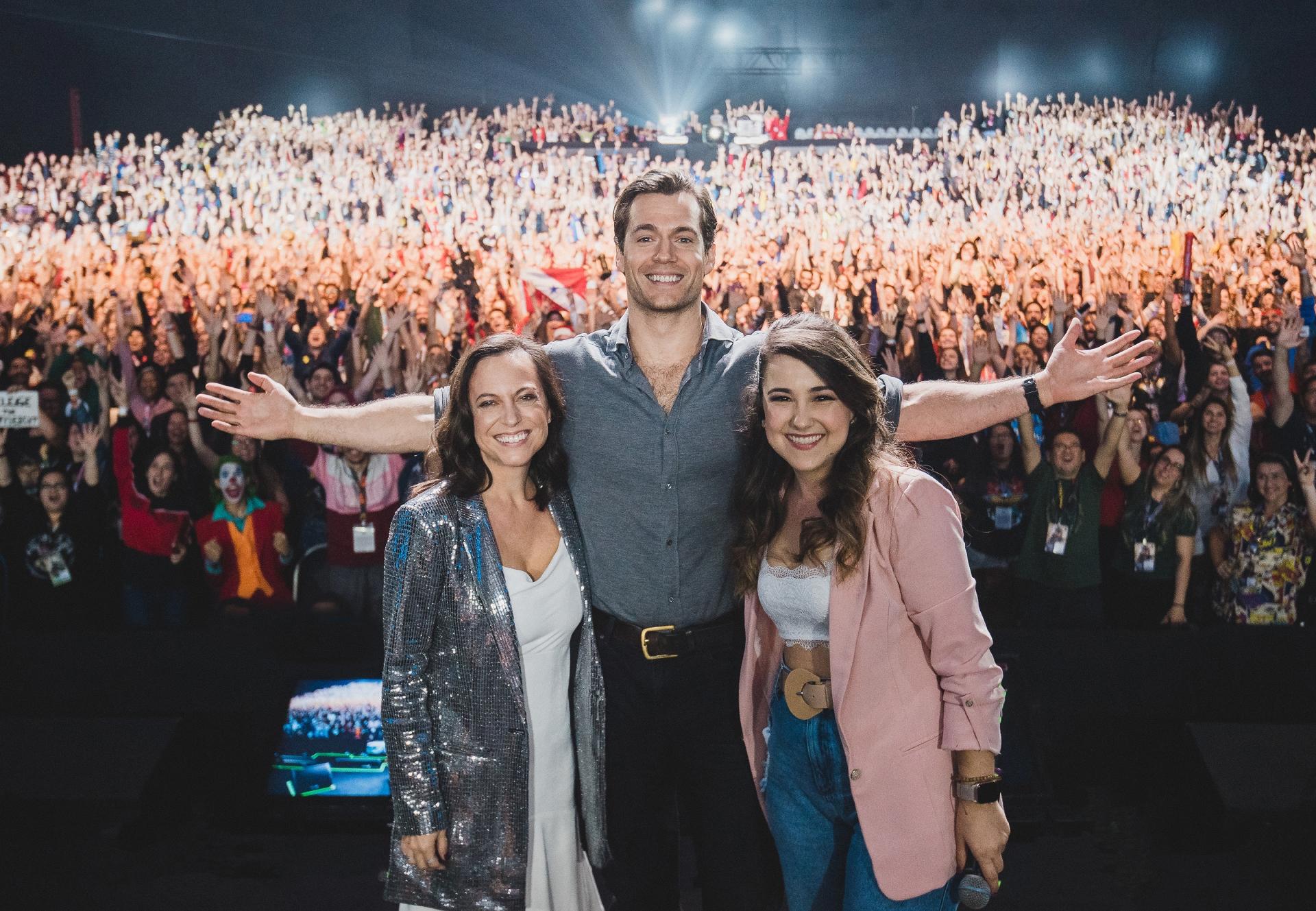 Henry Cavill posa no painel da Netflix na CCXP 2019 ao lado de Laurel Schmidt, criadora da série The Witcher, e da repórter Aline Diniz - Divulgação/Netflix