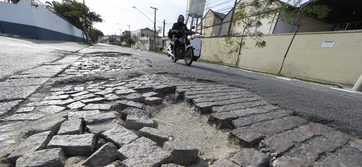 Moto passa por avenida desnivelada, esburacada e parcialmente asfaltada em São Paulo (SP): e o perigo de cair? - Robson Ventura/Folhapress