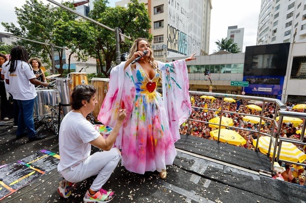 Artista pinta vestido branco de Daniela Mercury durante desfile do bloco Pipoca da Rainha, na rua da Consolação, em São Paulo - Marcelo Justo/UOL