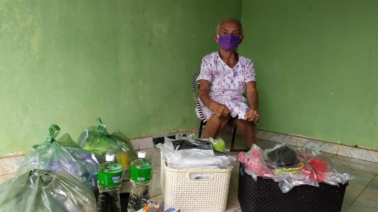 Vestindo máscara, dona Bernarda em frente a outras que costurou com a ajuda de nove amigas - Arquivo Pessoal