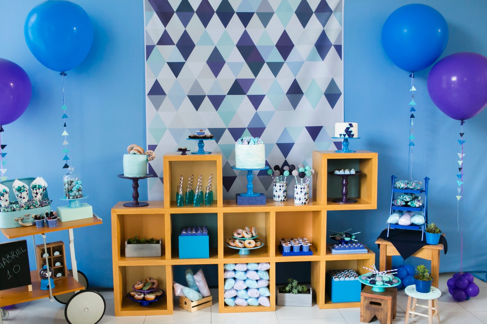 Um módulo de madeira com formato de cubos foi a escolha da Caraminholando (www.caraminholando.com.br) para a festa donuts, algodão doce e gostosuras. O bolo ficou no topo e os docinhos espalhados entre os espaços - Giselly Gonçalves/Divulgação
