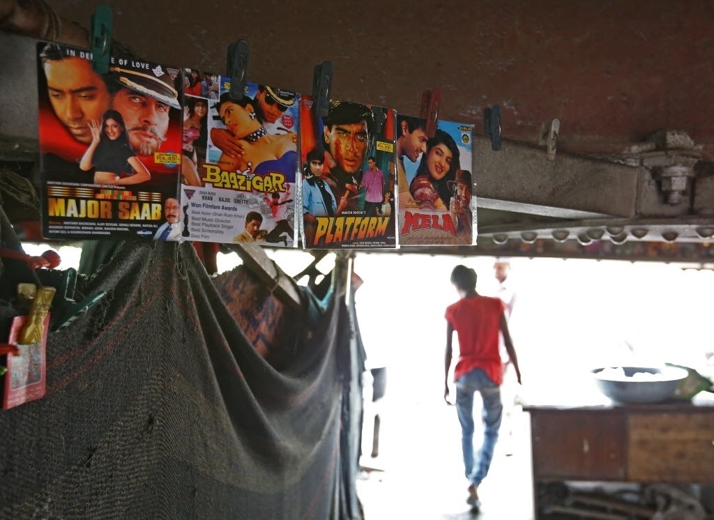 Catálogo de cinema de rua improvisado debaixo de uma ponte, na capital indiana, oferece cardápiode 4 filmes por dia. Filmes são produções da indústria de cinema local, conhecida como Bollywood - Cathal McNaughton/Reuters