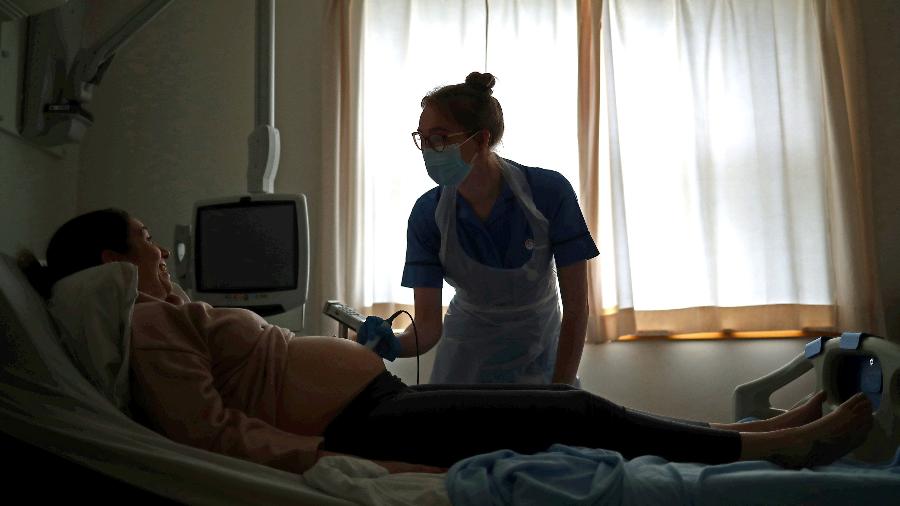Parteira checa batimentos cardíacos de bebê em mulher grávida durante a pandemia de coronavírus - Hannah McKay/PA Images via Getty Images