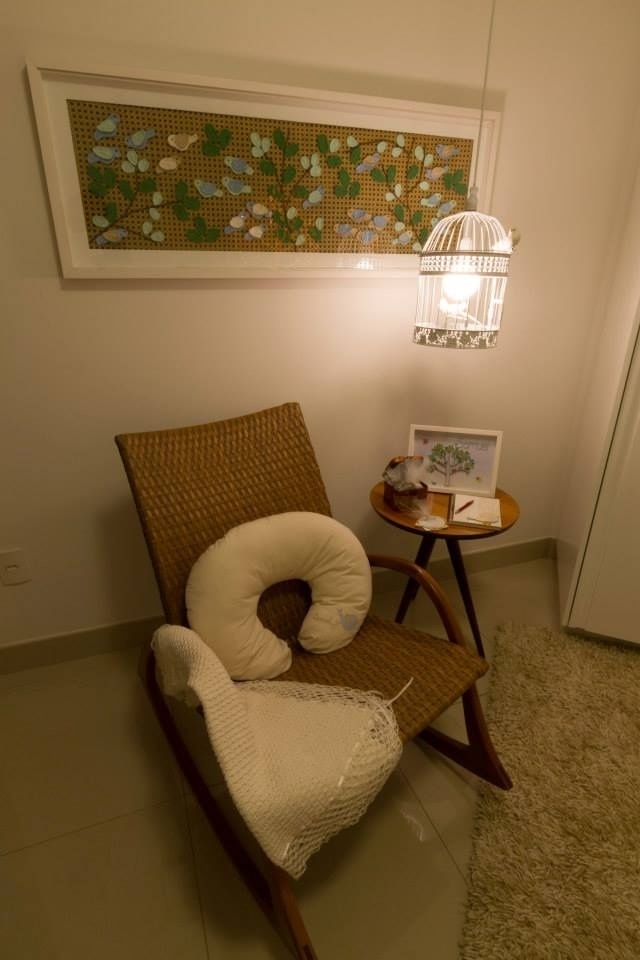Neste quarto do Acervo Arquitetura e Interiores, o destaque fica por conta do cantinho da amamentação. A cadeira de balanço é de rattan e o pendente foi feito pelo pai do bebê, a partir de uma gaiola comprada pronta. Já o quadro com fundo de palhinha, folhagens e pássaros de crochê foi produzido pela avó da criança - Ronaldo Gomes da Silva/Divulgação