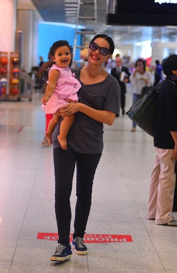 29.mar.2016 - 29.mar.2016 - A filha caçula de Carolina Ferraz já mostra que tem intimidade com as máquinas fotográficas. Nesta terça-feira (29), a menina de 11 meses era só sorrisos para os paparazzi na entrada do aeroporto Santos Dumont, no Centro do Rio de Janeiro. Com um vestido estampado rosa, Isabel se divertia no colo da atriz toda orgulhosa com a desenvoltura da criança - AgNews