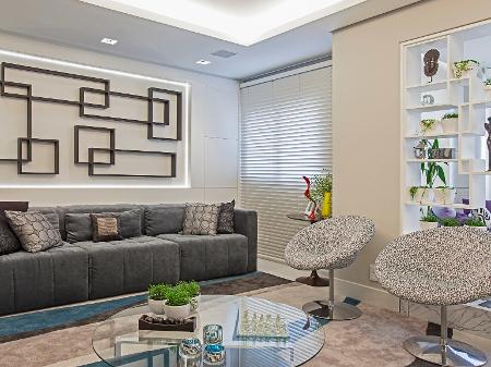 Na sala estar assinada por Cristiane Schiavoni, ao lado do painel com a peça de arte, à primeira vista as duas ?portinhas? podem passar desapercebidas. Mas, com um pequeno toque para abertura, os moradores têm acesso aos jogos de tabuleiros que estão guardados no espaço - Carlos Piratininga - Carlos Piratininga