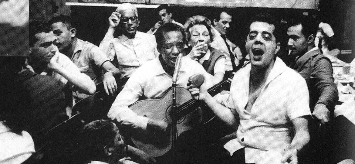 O músico e anfitrião, Cartola, observa o sambista Ismael Silva (ao violão), ao fundo, no bar Zicartola, no Rio de Janeiro, em 1969 - Acervo da Biblioteca Nacional/Divulgação