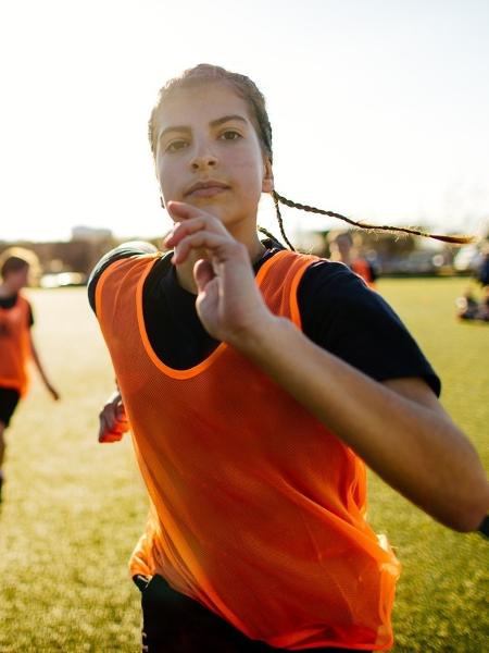 Menina jogando futebol mulher em campo