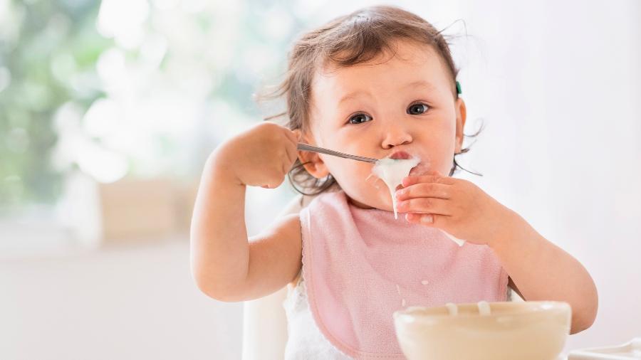 Criança faz refeição em uma cadeirinha para alimentação de bebês: item é muito importante na fase de introdução alimentar - Getty Images/Tetra images RF