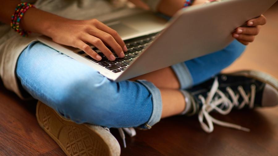 Menina jovem segura o notebook: é seguro permitir que os adolescentes usem o Omegle? - iStock