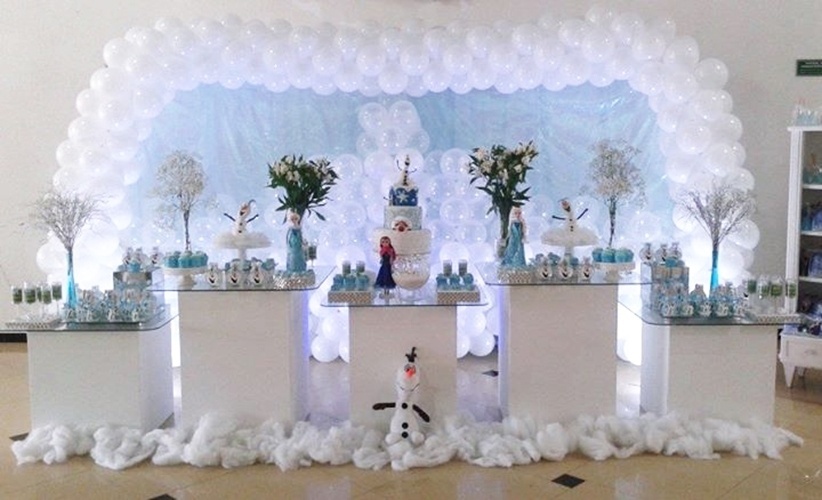 A festa com tema "Frozen", criada pela empresa Conto de Fada Decorações, (www.facebook.com/contodefadadecoracao) trouxe cinco módulos de mesas brancas, em diferentes tamanhos, e cobertas com tampo de vidro. As flores brancas e a espuma em todo o contorno remetiam à ideia de neve, como no filme - Divulgação