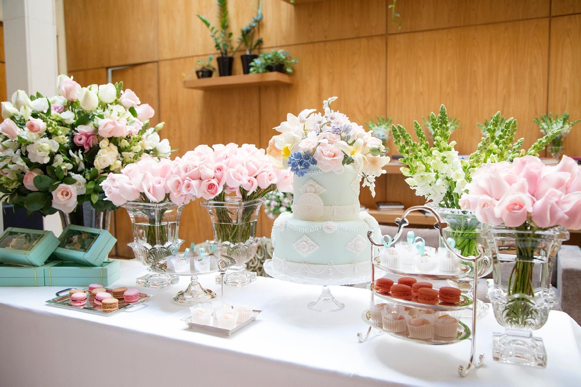 Nesta proposta, a delicadeza é o ponto chave da decoração e ela está em tudo: das flores espigadas e rosas spray aos doces, como o macaron. A paleta em tons pastel se mantém na mesa do bolo, uma das grandes atrações do casamento e que exige cuidado especial. Neste exemplo, a toalha de mesa é de linho. Vasos de cristal e bandejas e suportes prateados dão leveza e elegância à composição - Maíra Preto/ Divulgação