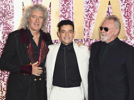 Brian May e Roger Taylor, do Queen, abraçam o ator Rami Malek, que intepreta Freddie Mercury no filme sobre a trajetória da banda - Jeff Spicer/Getty Images for Twentieth Century Fox