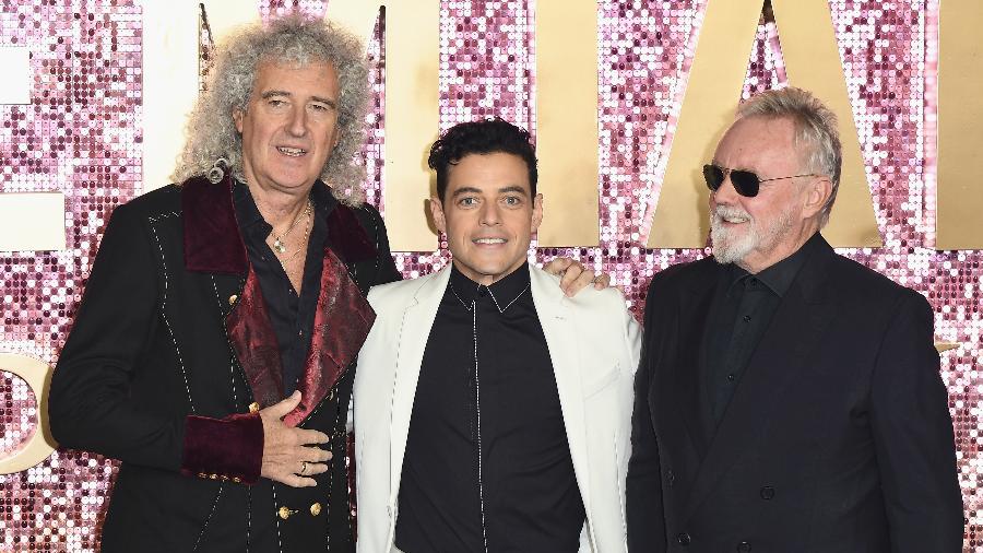 Brian May e Roger Taylor, do Queen, abraçam o ator Rami Malek, que intepreta Freddie Mercury no filme sobre a trajetória da banda - Jeff Spicer/Getty Images for Twentieth Century Fox