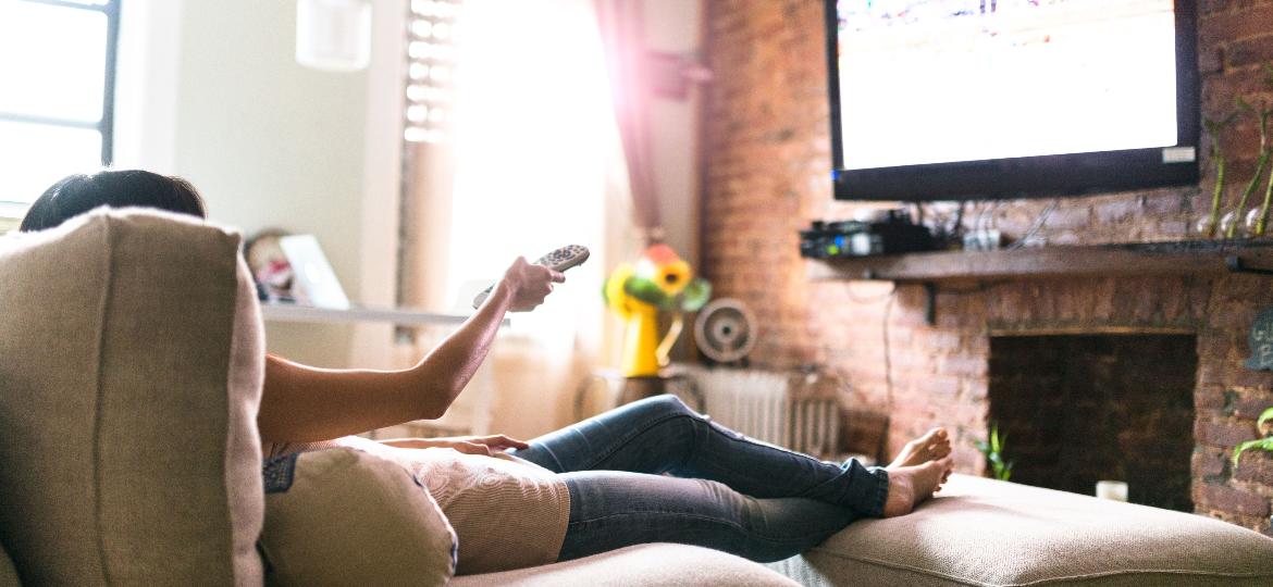 Mulher vendo a TV no sofá: elas ficam mais tempo (cerca de 37min/dia) diante do aparelho do que os homens - iStock