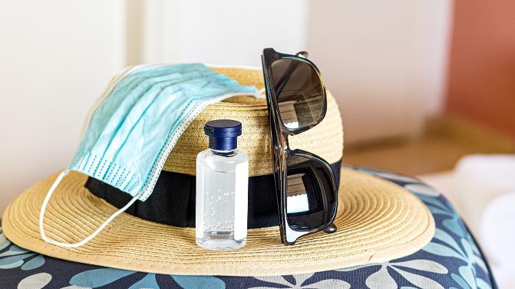 chapéu de praia com máscara e álcool em gel viagem covid - Getty Images/iStockphoto - Getty Images/iStockphoto