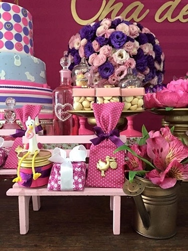 No centro do banco de madeira em a miniatura, alfajor de chocolate da Mondo Dolce (instagram.com/mondo_dolce_alfajor). Ao lado, arranjo de astromélias em minirregador na cor ouro velho - Divulgação