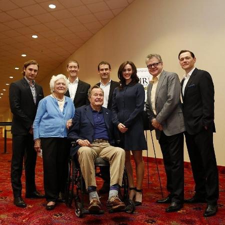 George H.W. Bush (na cadeira de rodas) teria aproveitado a foto para assediar Heather Lind (de azul, ao seu lado) em 2014  - Divulgação/AMC