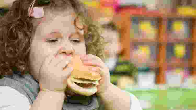 Criança comendo hambúrguer/ obesidade infantil - iStock - iStock