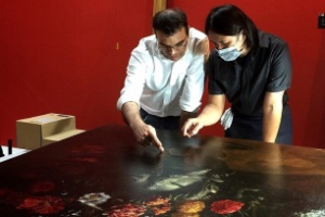 Funcionário do museu de Taipei e o restaurador Tsai Shun examinam os danos causados à pintura "Flores", de Paolo Porpora - Reprodução/TST Art of Discovery Co